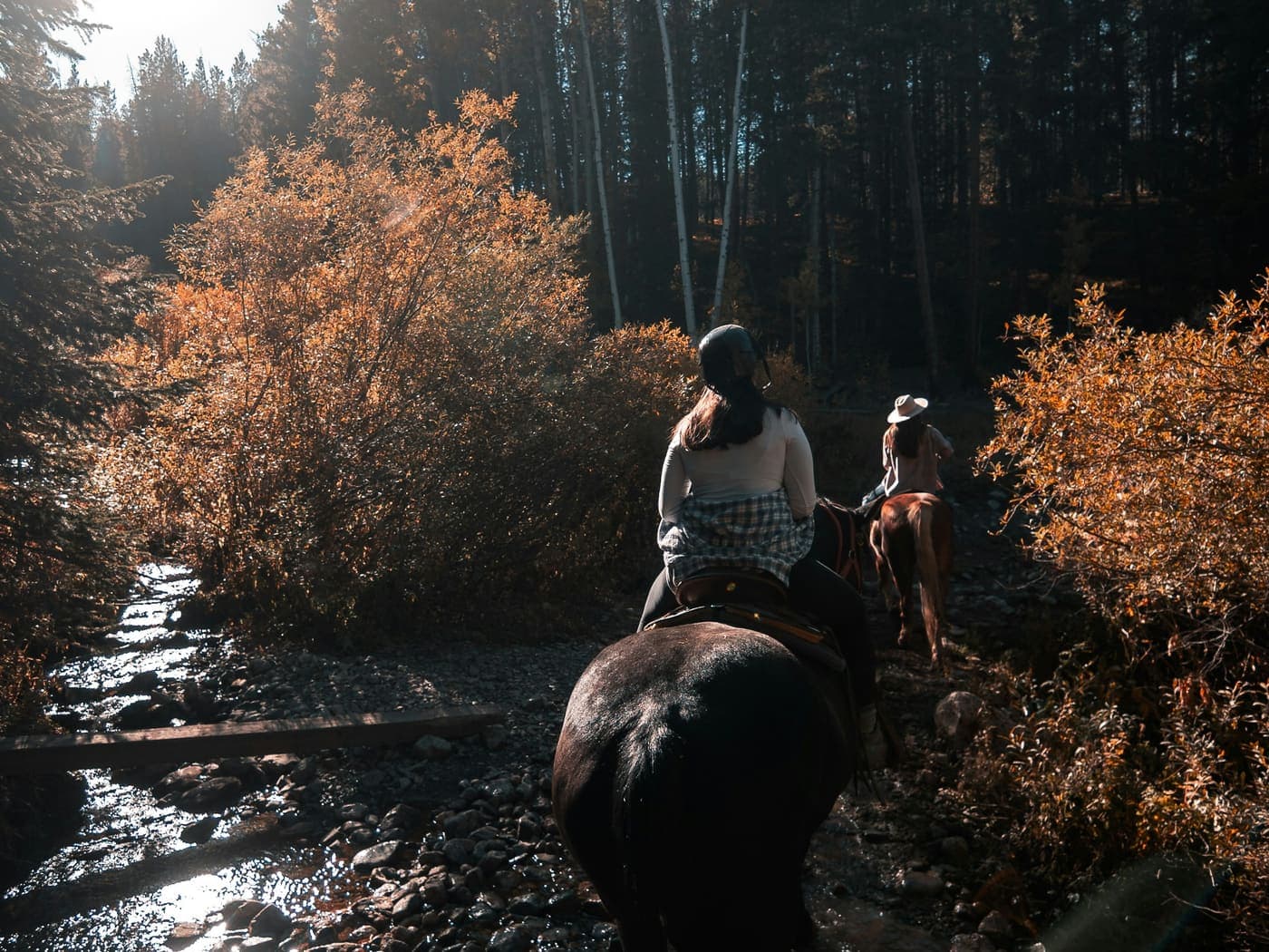 Dos personas cruzando un río a caballo