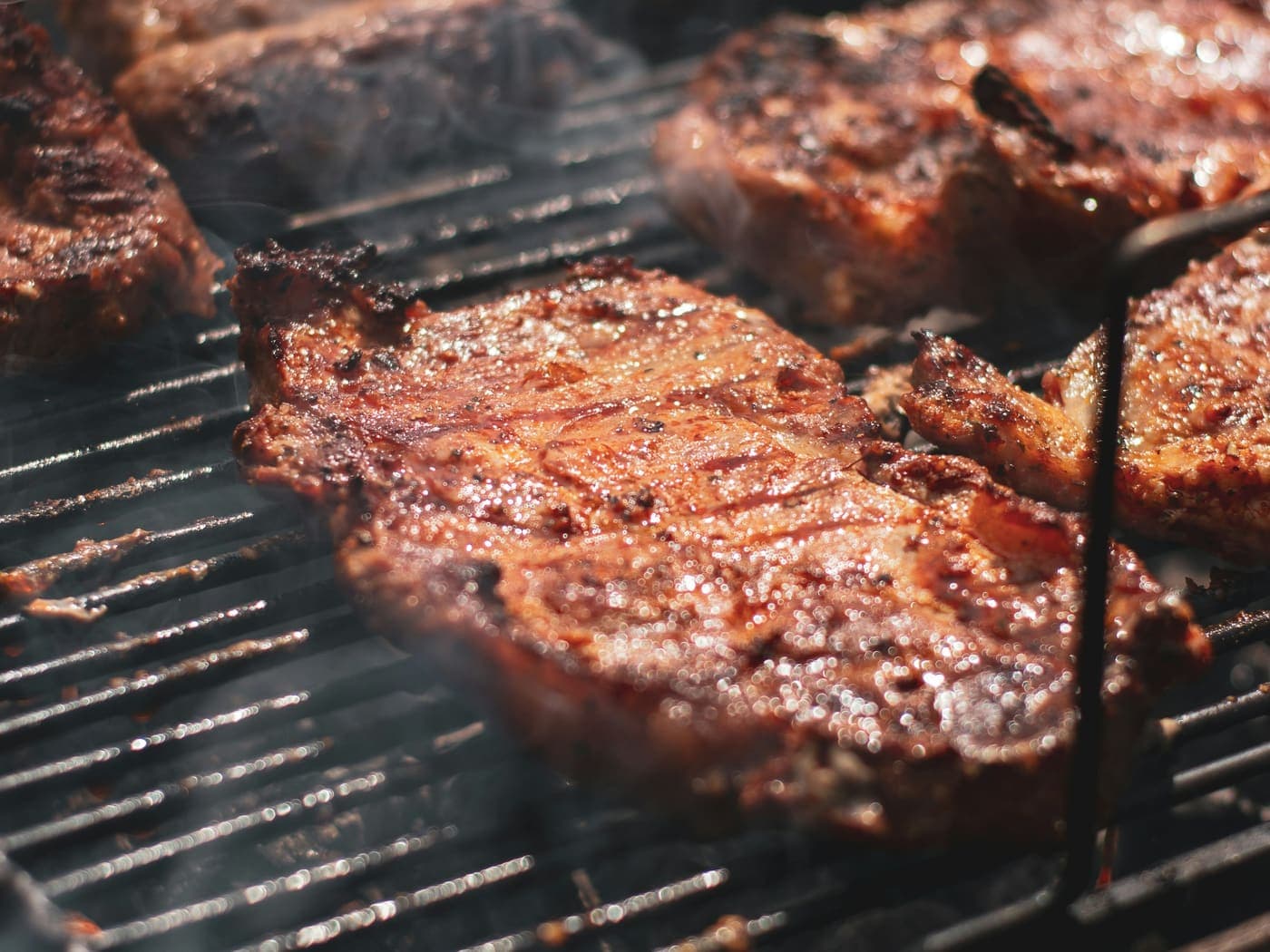 Carne asándose sobre una parrilla a carbón
